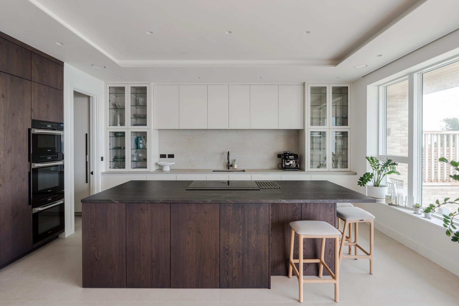 Fitted kitchen with dark timber island, white cupboards and integrated ovens at Bexhill-on-Sea