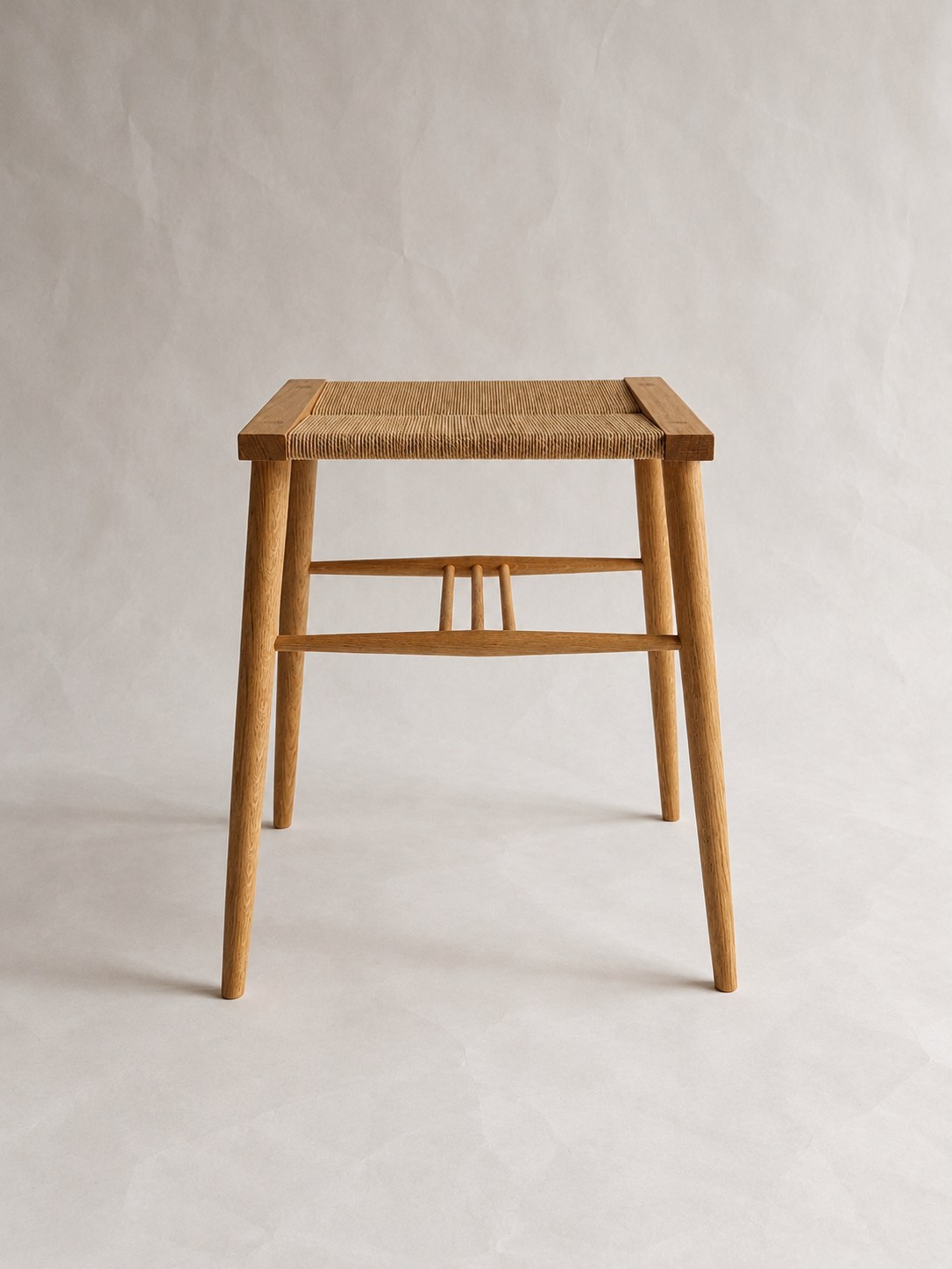 Front view of the Shibui Stool with woven seat and tapered legs