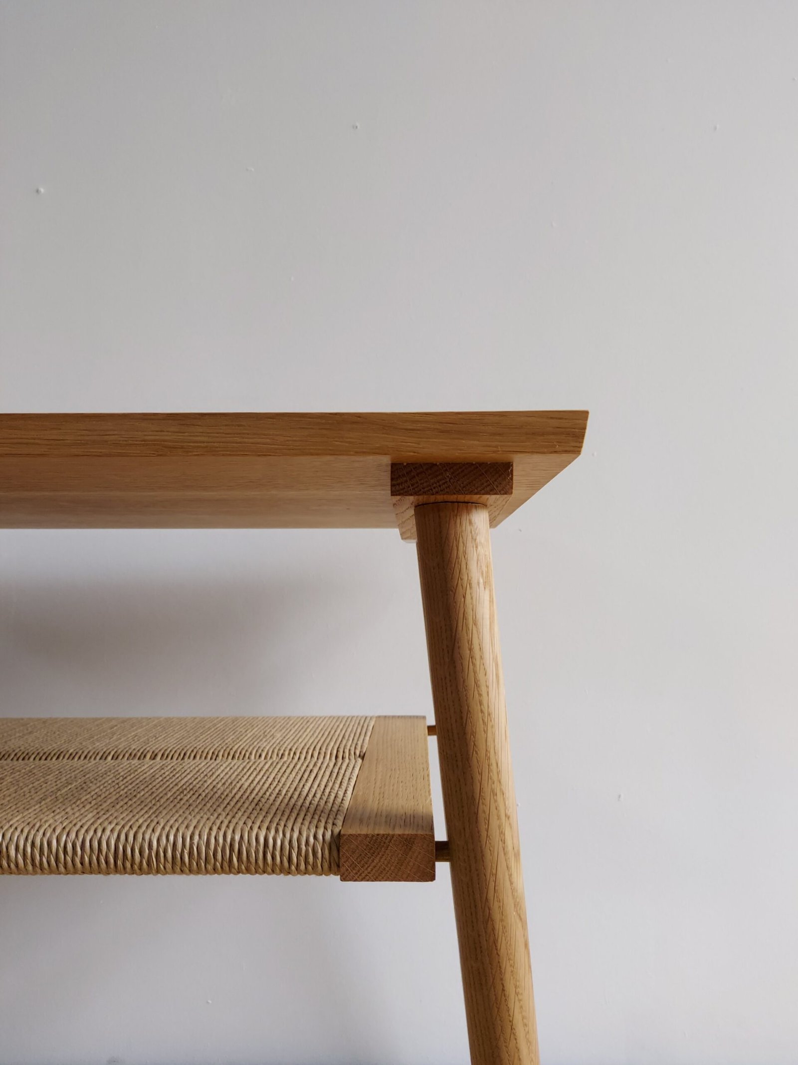 Shibui Side Stand leg and woven lower shelf beneath the shaped tabletop